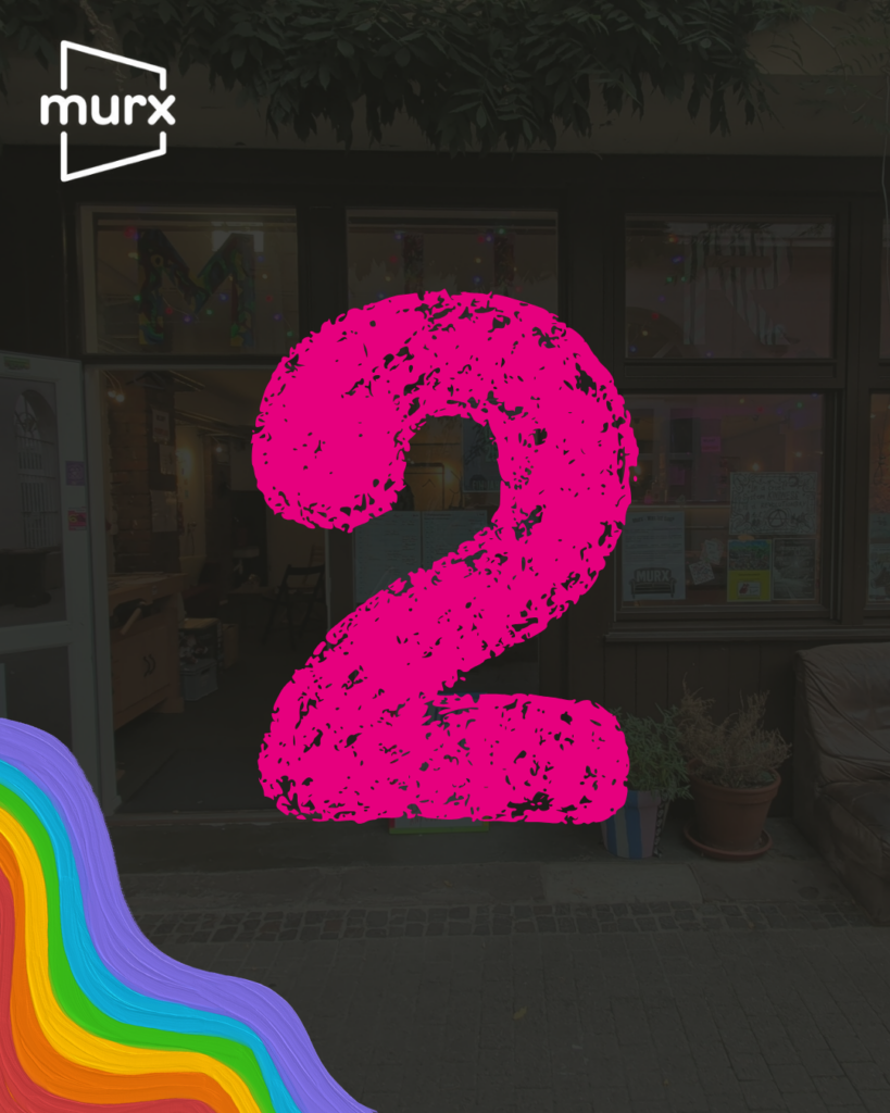Bild in dessen Hintergrund ein etwas abgeblendetes Bild des Murx von Außen ist. | Links oben das Murx-Logo, Links unten ein Regenbogen in Pastellfarben, in der Mitte eine große 2 die wie mit Kreide geschrieben aussieht.